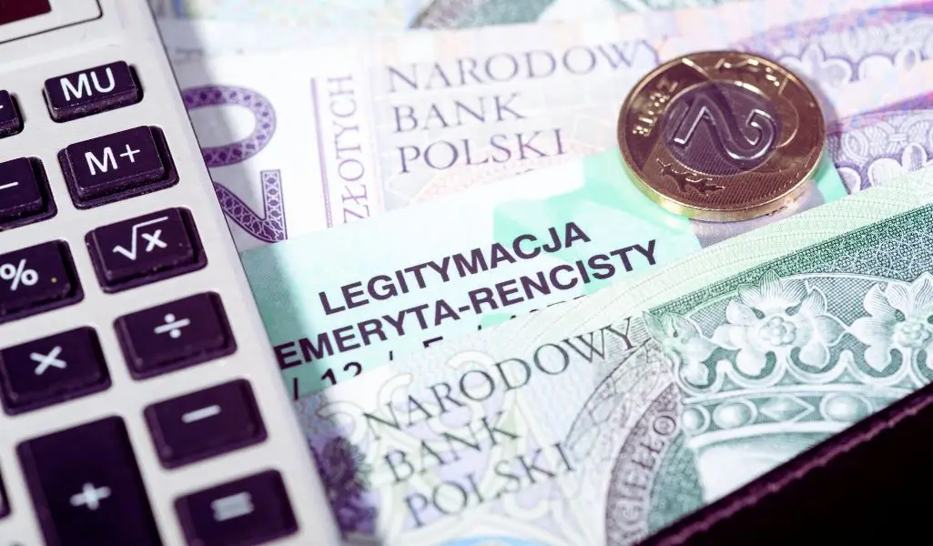 Na zdjęciu widzimy polskie banknoty i monety, które symbolizują kwestie finansowe, takie jak emerytury czy renty. W centralnej części widoczna jest legitymacja emeryta-rencisty, co sugeruje kontekst wsparcia dla seniorów lub osób na rencie. Obok leży kalkulator, co wprowadza nastrój związany z kalkulowaniem wydatków, dochodów lub świadczeń. Całość tworzy obraz poruszający temat wsparcia finansowego, takiego jak Dodatek dopełniający, który może być kluczowy w budżecie domowym osób starszych.